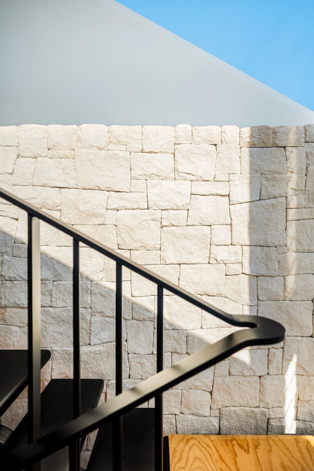 Split-face sandstone feature wall beside a black steel staircase